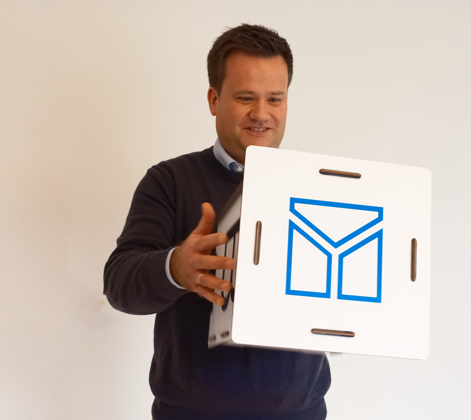 Ein Mann hält einen Karton mit dem TBE Logo darauf - TBE ingenieurbüro für Tragwerksplanung