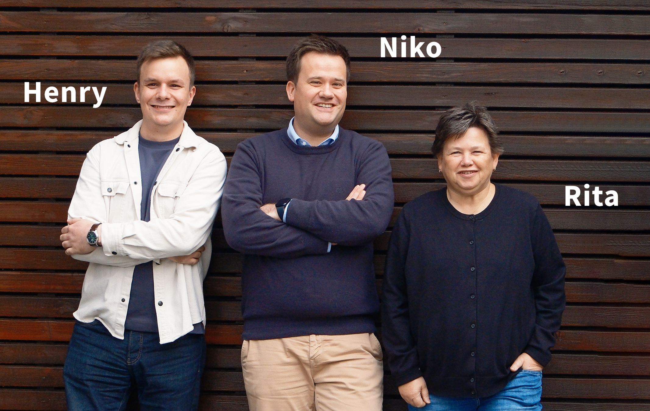 Zwei Männer und eine Frau stehen vor einer braunen Holzwand und schauen in die Kamera - TBE ingenieurbüro für Tragwerksplanung