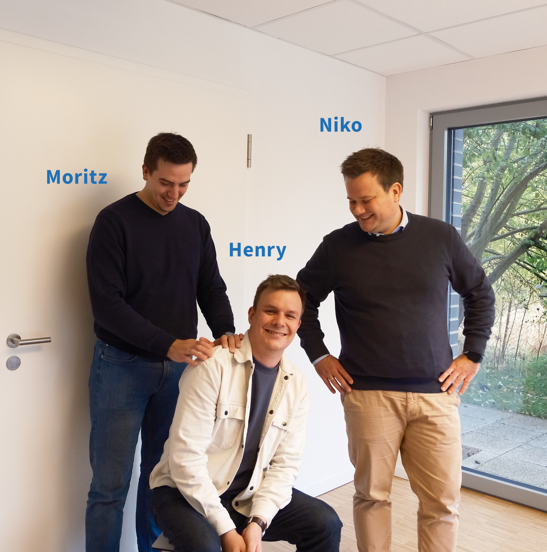 Zwei Männer stehen neben einem Mann der sitzt in einem Raum - TBE Ingenieurbüro für Tragwerksplanung